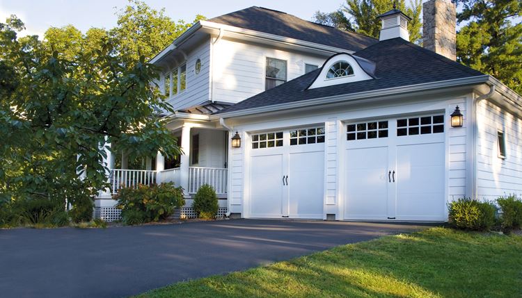 Two-car garage doors on large white home.