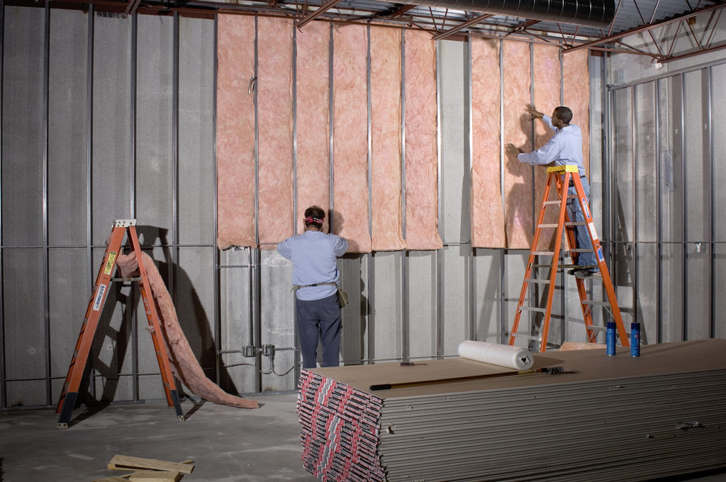 Two technicians installing insulation in a commercial building