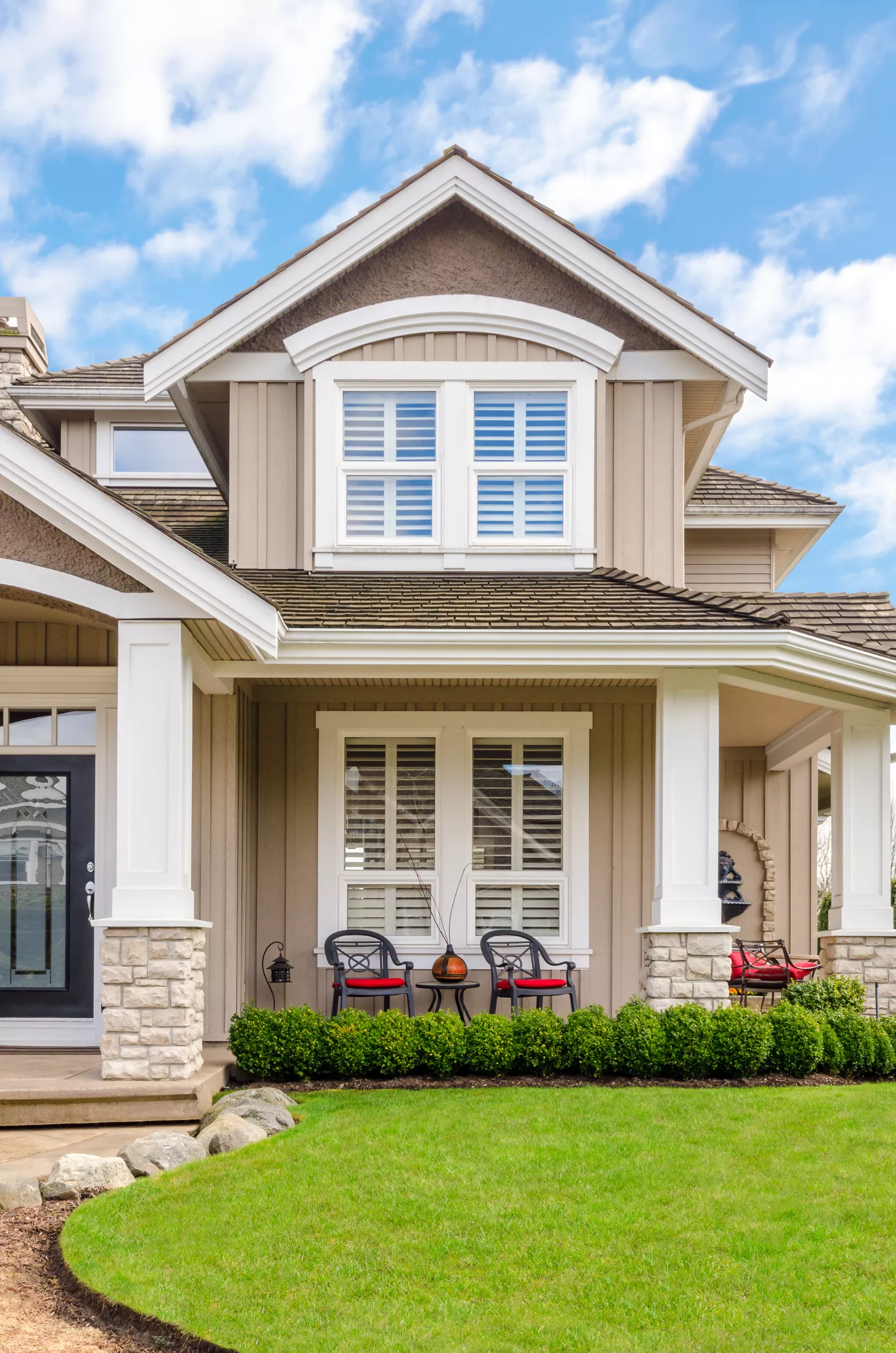 Exterior view of two-story brown home with faux-wood blinds visible inside the large windows.