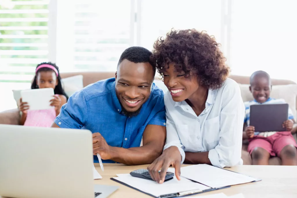 Couple calculating energy bills at home on laptop.