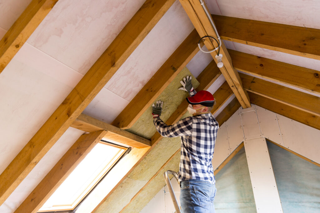 Insulation contractor installing rigid foam insulation in an attic ceiling
